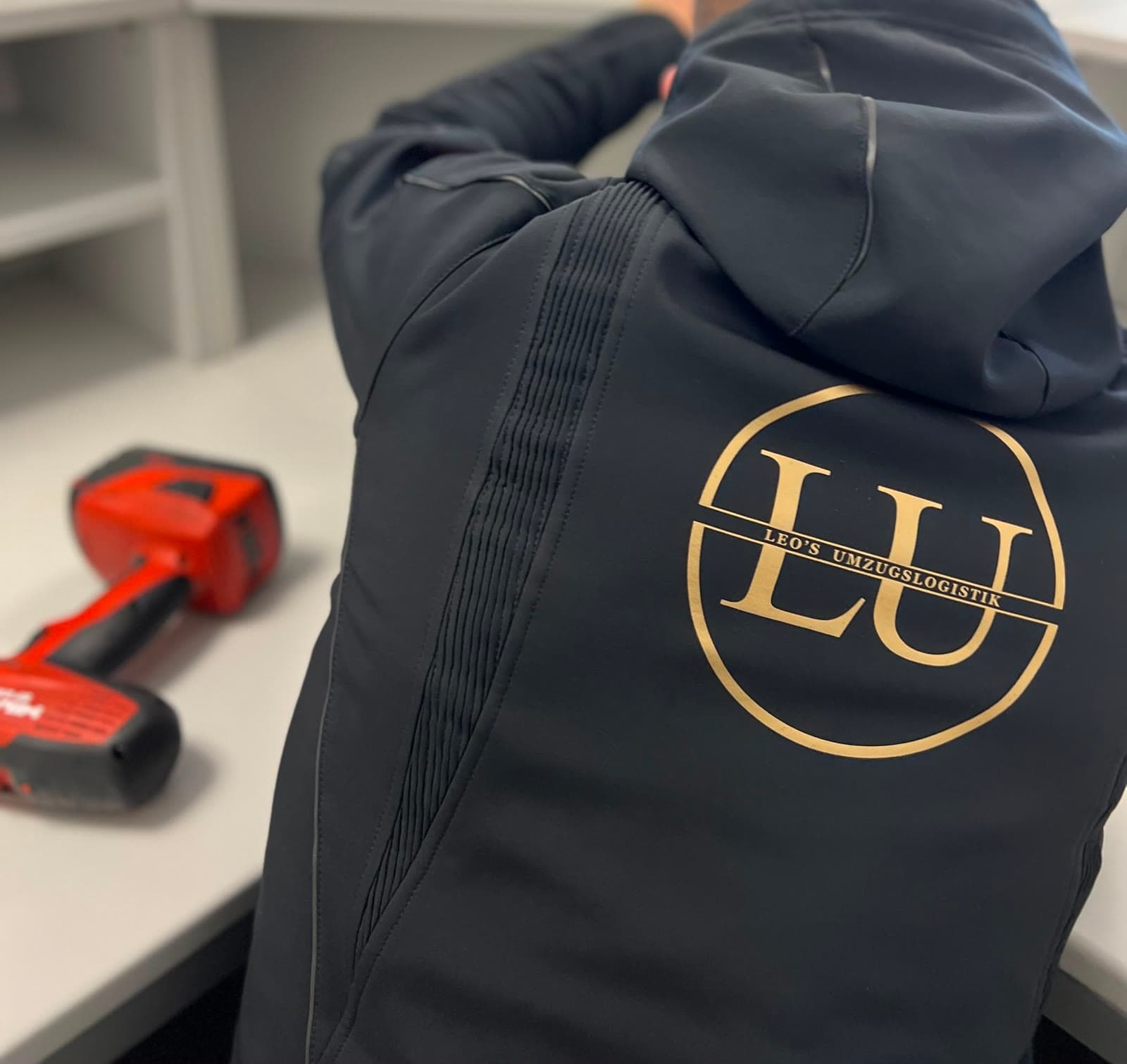 Arbeitsjacke mit dem Logo von Leos Umzugslogistik neben Akkuschraubern