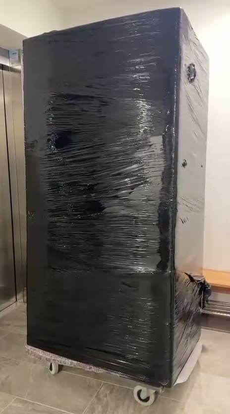 Vollständig folierter Hochschrank auf dem Möbelroller vor dem Aufzug